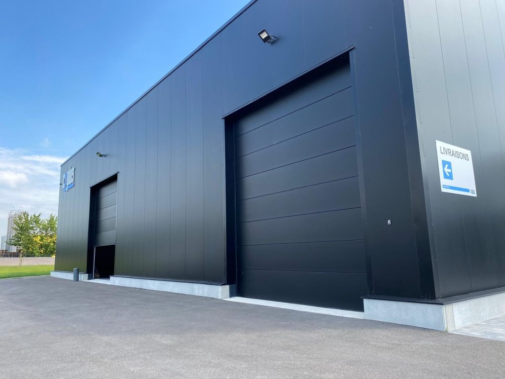 Porte de garage sectionnelle industrielle avec panneaux isolants, installée sur un bâtiment commercial