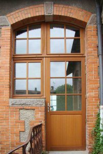grande porte dentrée vitrée cintrée en bois fabriquée sur mesure pour une maison en brique roue apparentes menuiserie marquis